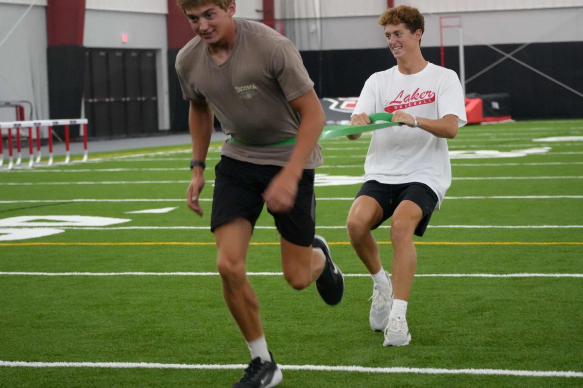Lucas Williams (left) and Alex Strauss get to work on the new fieldhouse turf. 